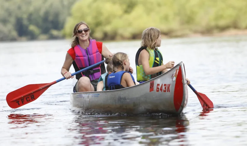 Family canoeing together on a peaceful river wearing life jackets